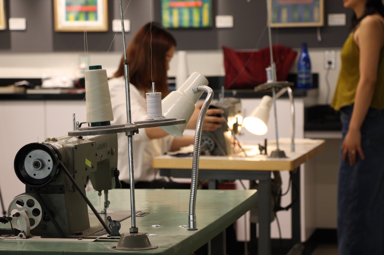 studio space in progress, line of sewing machines and students working 